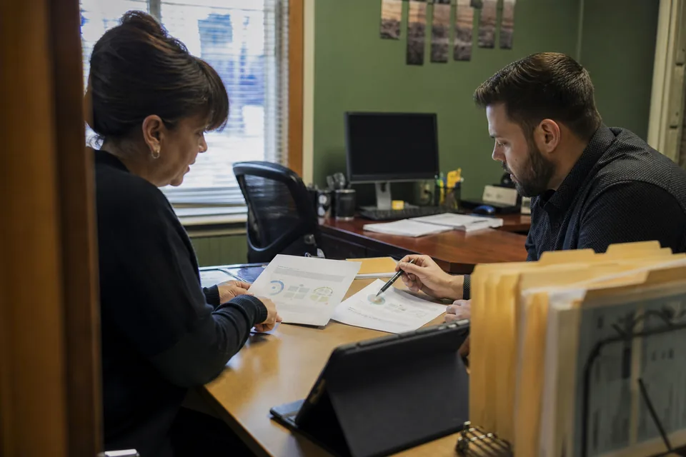 Owner of a small property management office reviewing two software quotes with a colleague before choosing a signing tool